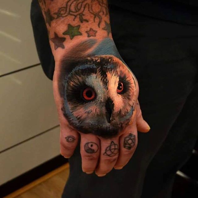 Full colored realistic owl on hand